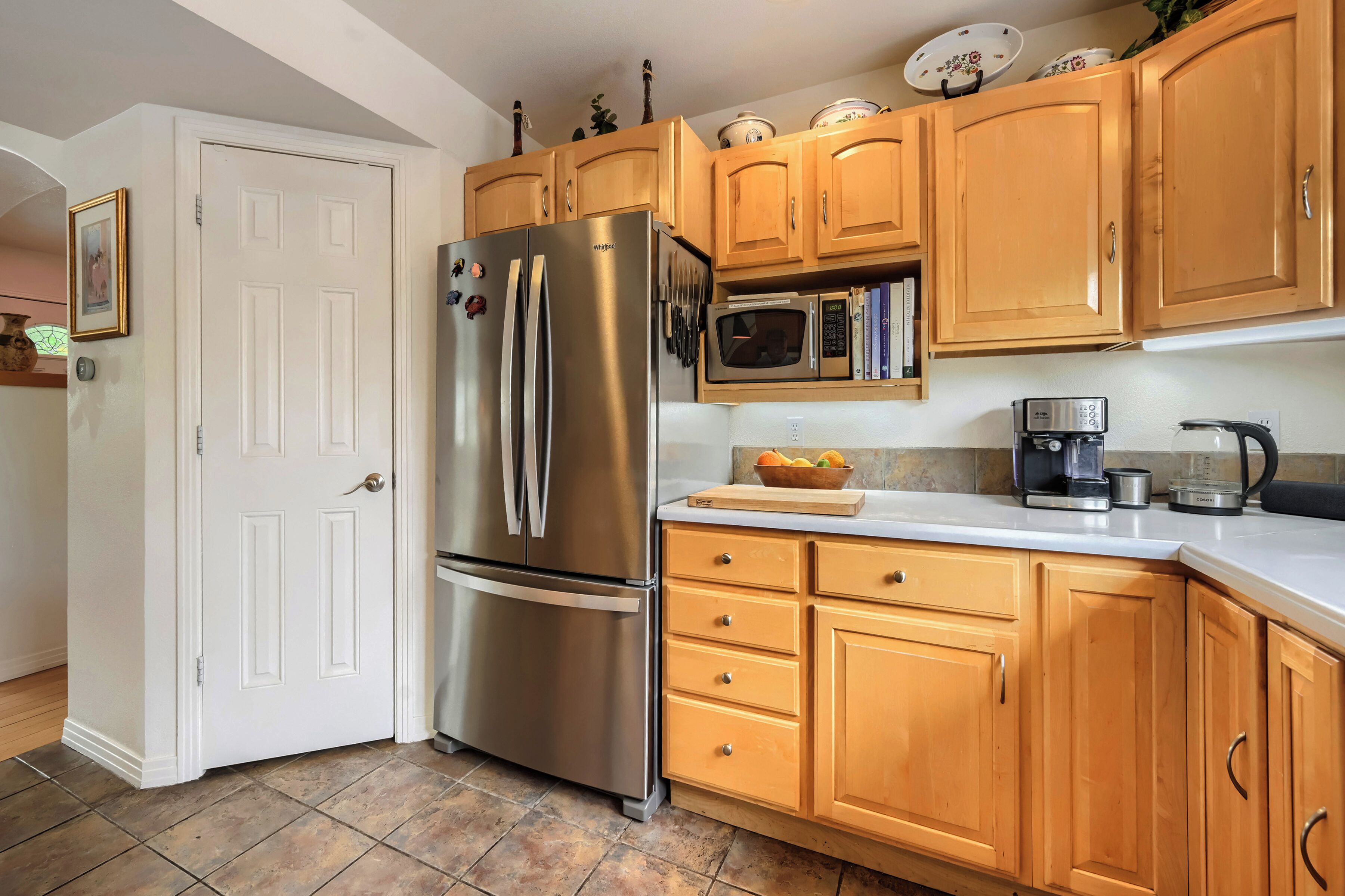 A kitchen with wooden cabinets, a stainless steel refrigerator, a microwave, and a coffee maker.