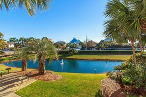 A park with a pond, benches, and palm trees.