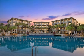 A hotel with a pool, multiple balconies, and palm trees.