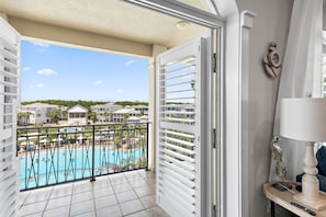 A balcony with a view of a swimming pool and resort buildings.