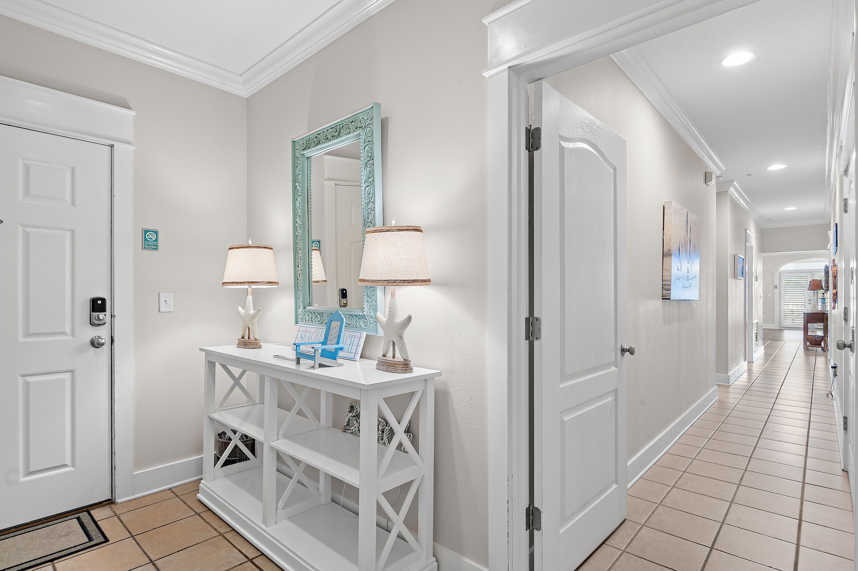 A hallway with white doors, a console table with a mirror, two lamps, and a starfish decoration.