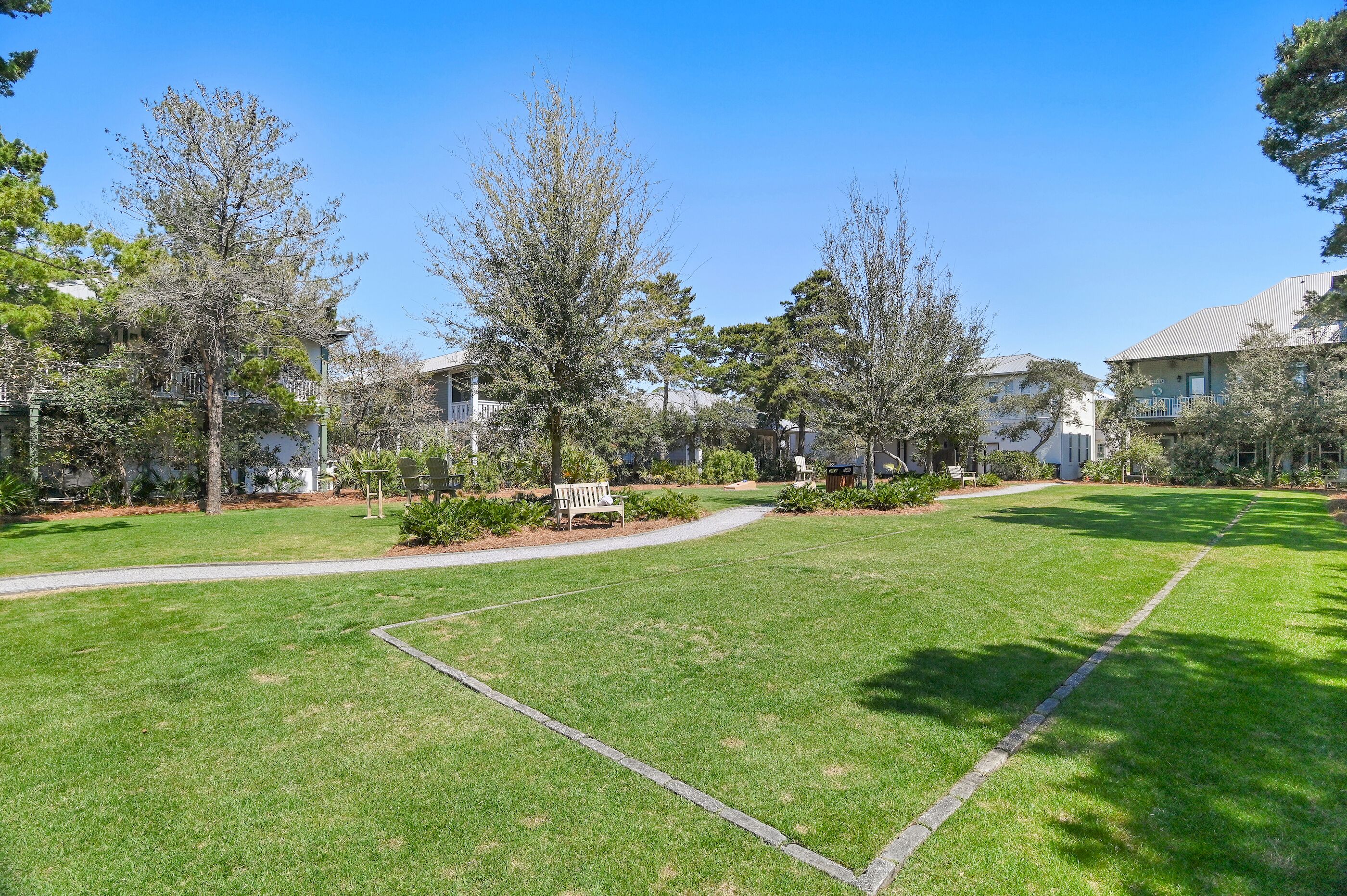 A well-maintained lawn with a bench, trees, and a pathway leading to a building.
