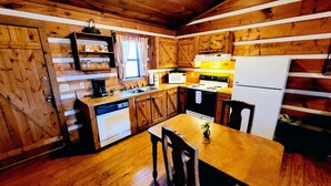 A rustic kitchen with wooden cabinets, a stove, a sink, and a dining table with chairs. - B's Nest a Private & Clean w Mtn Views & Hot Tubs! (Sevierville)