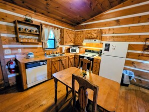 A wooden cabin-style kitchen with a wooden table and chairs, a sink, a stove, and a refrigerator.