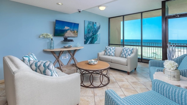 A spacious balcony with a view of the ocean, furnished with two sofas and a round table. - *Roll-in Shower* Wheelchair Accessible Beach Front Hotel Suite (Gulf Shores)