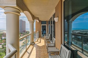 Un balcon avec vue sur l’océan et un immeuble de grande hauteur.