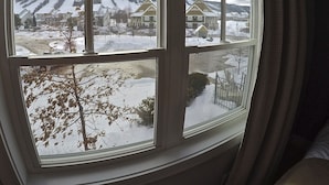 A view through a window with a view of a snowy landscape, houses, and a tree. - Short walk to the village-Stunning upgraded Rivergrass condo w/ beautiful decor (The Blue Mountains)