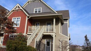 A two-story residential building with a balcony, a staircase, and a door. - Short walk to the village-Stunning upgraded Rivergrass condo w/ beautiful decor (The Blue Mountains)