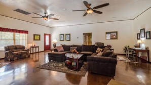 A spacious living room with hardwood floors, a large sectional sofa, a coffee table, and two ceiling fans. - Hannah House ~ Your Vacation Awaits! (Huntsville)