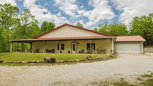 A two-story building with a red roof and beige walls, featuring a covered porch with outdoor seating. - Hannah House ~ Your Vacation Awaits! (Huntsville)