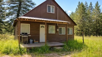 A small log cabin with a porch, a door, and a window.