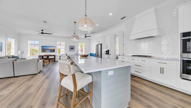 Una cocina moderna con armarios blancos, una isla grande y piso de madera.