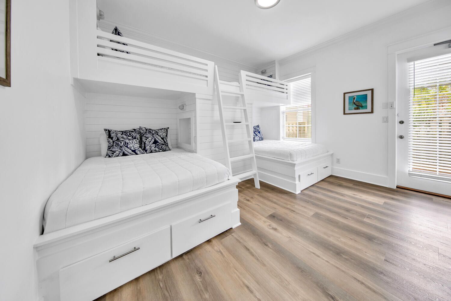 A bedroom with a bunk bed, a desk, and a window with blinds.