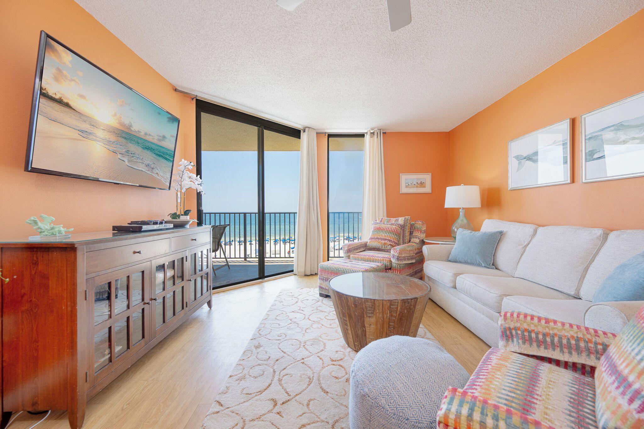 A room with a balcony, a sofa, a chair, a coffee table, and a cabinet.