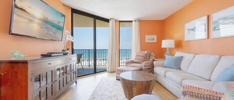 A room with a balcony, a sofa, a chair, a coffee table, and a cabinet.