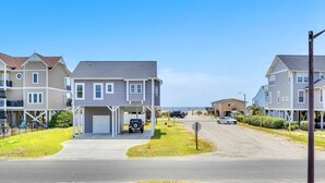 A residential street with houses, a driveway, and a clear sky. - Sunkissed 2: Comfortable Cottage Near Public Beach Access (Oak Island)