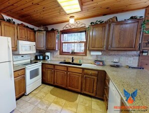 Une cuisine avec des meubles en bois, un réfrigérateur blanc, un four à micro-ondes et une cuisinière.