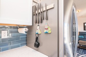 Enjoy cooking in this well-equipped kitchen with a stainless steel refrigerator, magnetic knife strip, and blue-tiled backsplash.