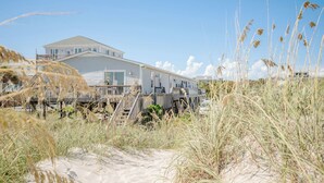 A beach house with a deck and a large window overlooking the beach.