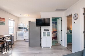 Enjoy a stylish living space with a kitchen area, flat-screen TV, and comfortable seating.