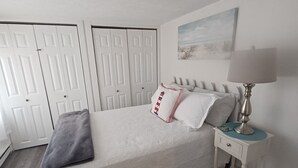 A bedroom with a bed, bedside table, lamp, and a painting on the wall. - Lake Erie Cottage w/ Private Beach Access - Couples Retreat (Madison)