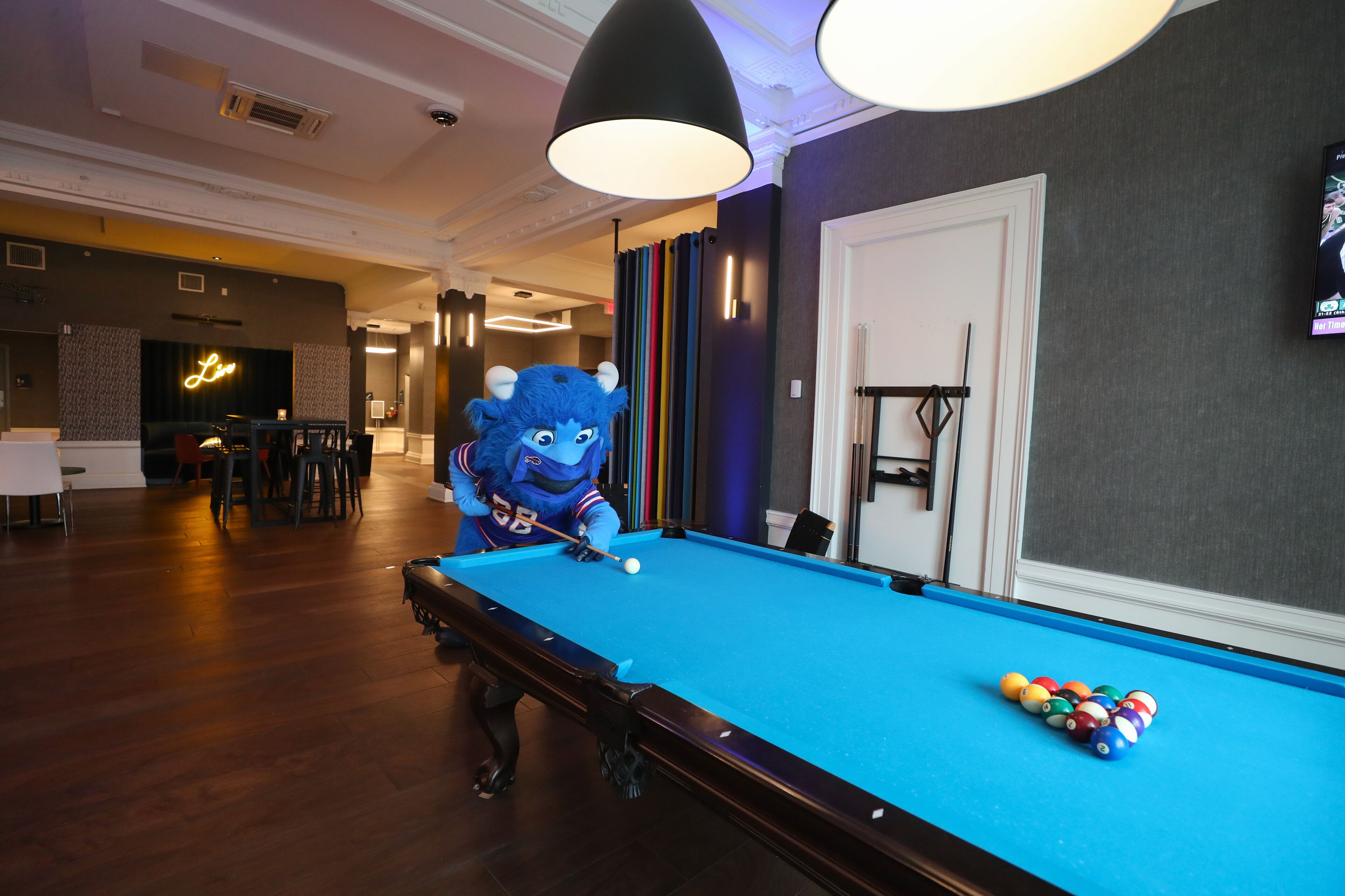 A pool table with a blue felt surface, surrounded by a wooden floor.