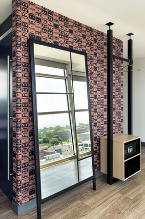 Una habitación con un espejo grande, papel tapiz estampado, un aparador de madera y vistas a la ciudad.