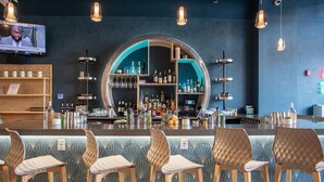 A bar area with a circular bar counter, multiple hanging light fixtures, and bar stools. - Aloft by Marriott Buffalo Downtown (Buffalo)