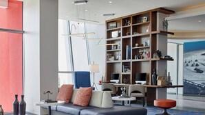 Una moderna hall d'hotel con un'area salotto, un'ampia libreria e una scrivania con un computer.