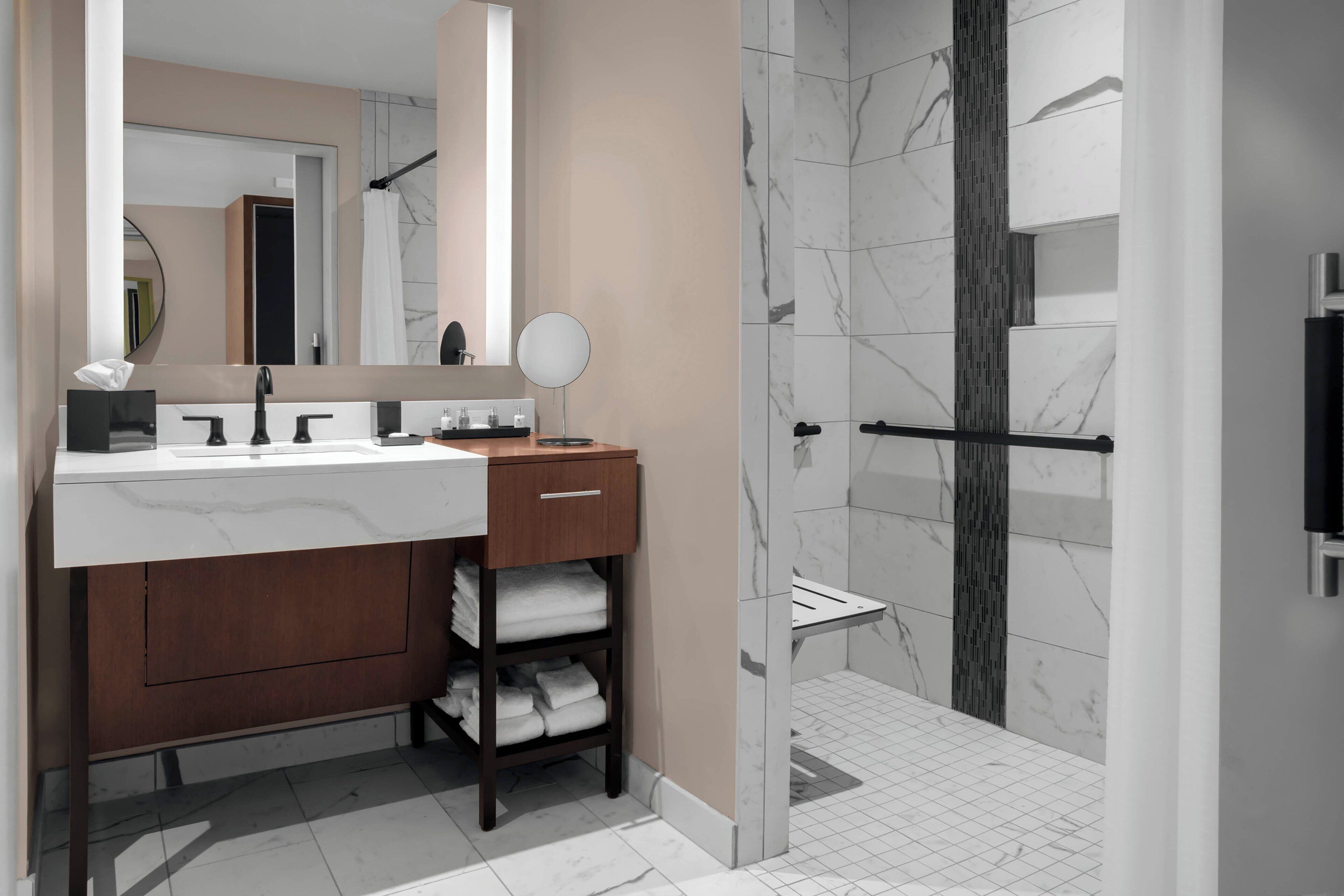 A modern bathroom with a marble sink, wooden vanity, and a glass-enclosed shower area.