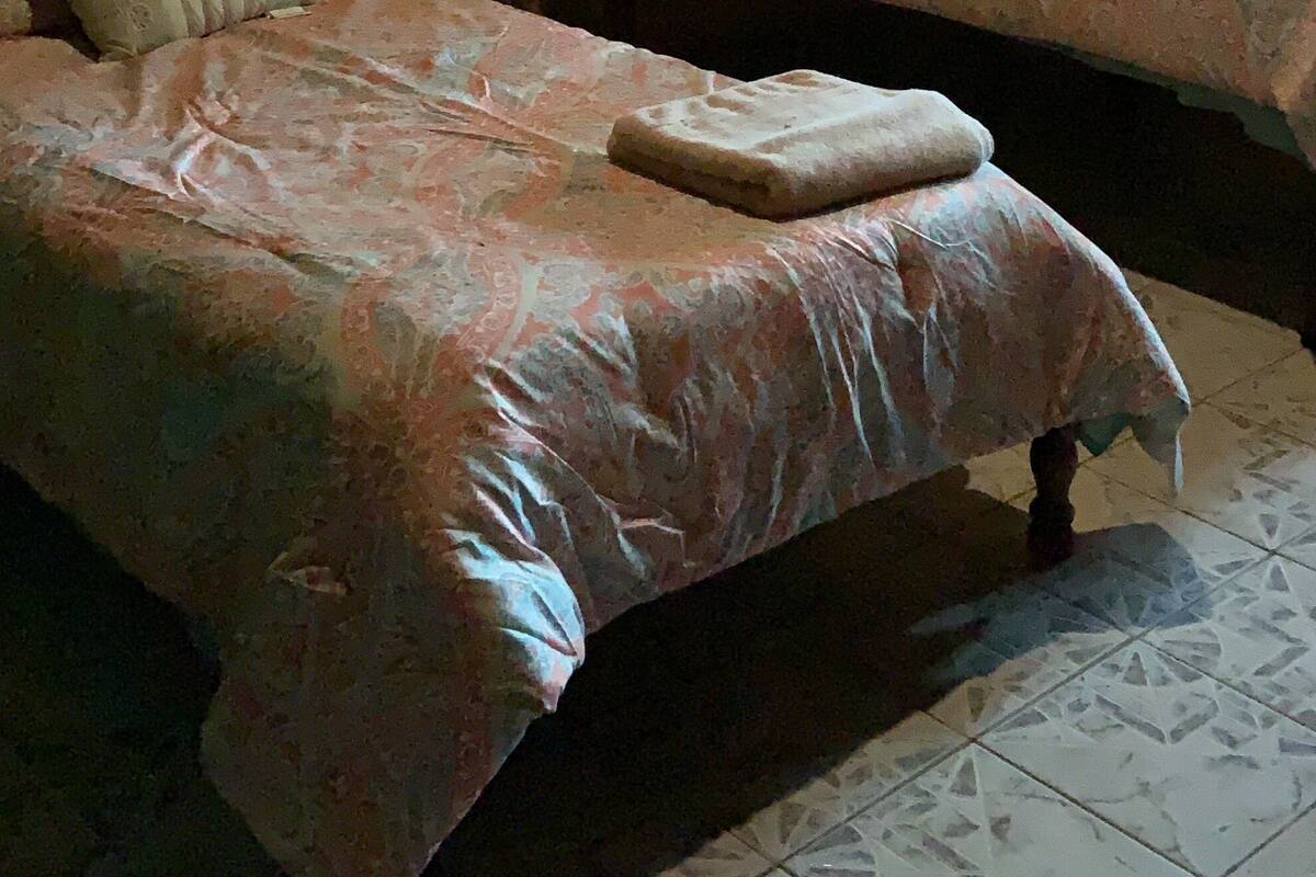 Two single beds with floral bedspreads, a nightstand, a lamp, and a wall-mounted tree decoration.