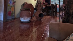 Een rustiek interieur met een houten plafond, terracotta potten en een decoratieve wand met bloemkunst.