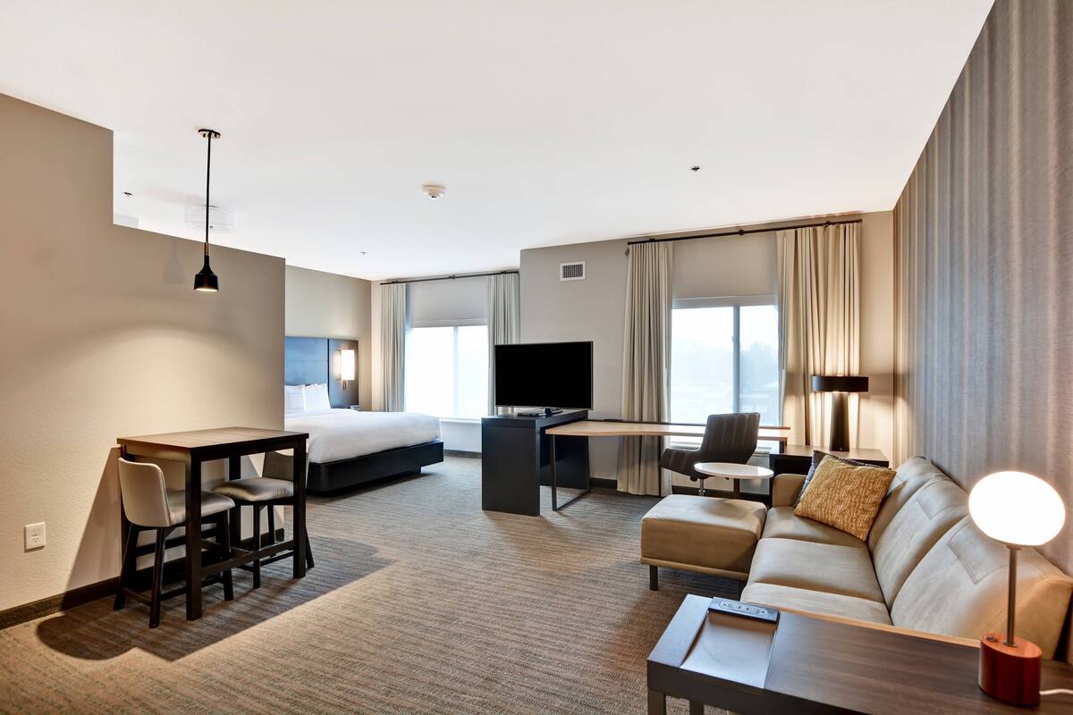 Une chambre d’hôtel moderne équipée d’un lit, d’un bureau, d’un canapé, d’une télévision et d’une lampe.