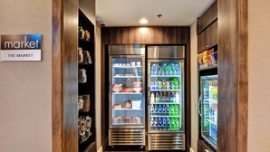 A hallway with two refrigerated display cases stocked with snacks and beverages, and a sign indicating 'The Market'. - Residence Inn by Marriott Cleveland Airport/Middleburg Heights (Middleburg Heights)