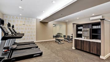 Un gimnasio moderno con cintas de correr, pesas y un espejo grande.