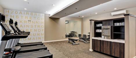 A modern gym with treadmills, weights, and a mirrored wall.