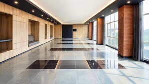 A modern hallway with wooden paneling, a black-tiled floor, and large windows. - ibis Styles Bekasi Jatibening (Bekasi)