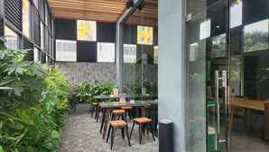 An outdoor seating area with stone walls, glass partitions, and various plants. - ibis Styles Bekasi Jatibening (Bekasi)