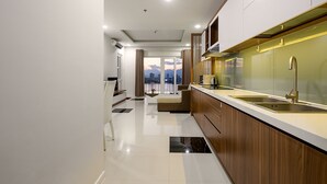 A modern kitchen with a large island, a built-in oven, and a view of the cityscape through the window.