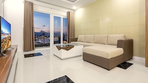 A modern living room with a sofa, a glass coffee table, and a TV on a wooden stand.