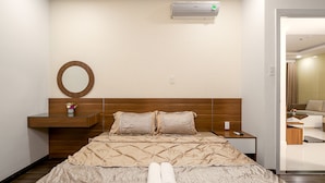 A hotel room with a bed, a bedside table, a mirror, and a wall-mounted air conditioner.