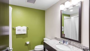A bathroom with a green wall, white toilet, and a sink with a mirror.