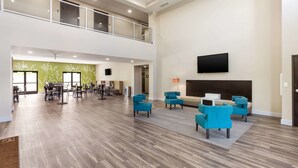 A spacious lobby with a high ceiling, a balcony, and a flat-screen TV mounted on the wall. - Sleep Inn Logan Ohio-Hocking Hills (Logan)