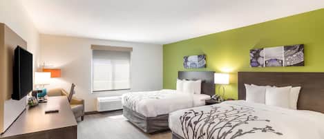 A hotel room with two beds, a desk with a TV, a window, and artwork on the walls.