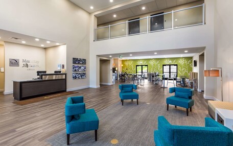 A spacious lobby with a reception desk, multiple seating areas, and a green wall with floral decorations.
