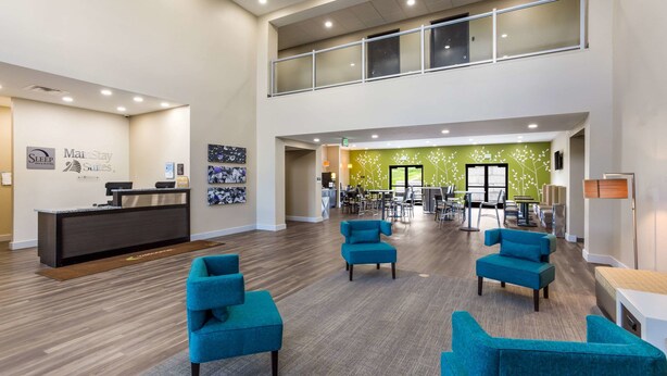 A spacious lobby with a reception desk, multiple seating areas, and a green wall with floral decorations. - Sleep Inn Logan Ohio-Hocking Hills (Logan)
