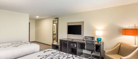 A hotel room with two beds, a desk with a computer, a TV, and a chair.