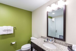 A bathroom with a green wall, white toilet, and a sink with a mirror above it.