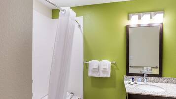 A bathroom with a shower curtain, a sink with a mirror, and a towel rack with two towels.
