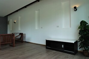 Una habitación con un banco de madera, un mueble negro para entretenimiento y una planta en maceta.